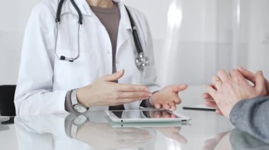 Doktor, klinik muayenesi, profesyonel bakım tartışması sırasında tıbbi verileri incelemek için tablet kullanan hastaya tedavi seçeneklerini açıklıyor. İlaç ve sağlık hizmetleri