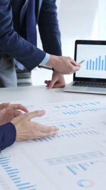 Masanın üzerinde duran ve mali verileri tartışırken mali tablolara işaret eden bir işadamı, ofiste yapılan bir şirket toplantısında piyasa eğilimleri. İş adamları konsepti.