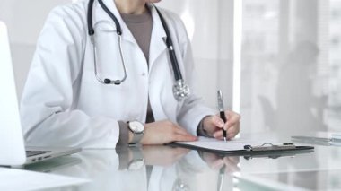 Panoya yazı yazan, steteskop takan, ilaç, sağlık, teşhis ve tedavi kavramlarını yansıtan beyaz önlüklü bir doktor. İlaç ve sağlık hizmetleri