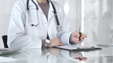 Panoya yazı yazan, steteskop takan, ilaç, sağlık, teşhis ve tedavi kavramlarını yansıtan beyaz önlüklü bir doktor. İlaç ve sağlık hizmetleri