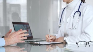 Doktorlar, modern bir klinikte muayene sırasında bir hastayla iletişim kurar, tıbbi seçenekleri açıklar ve profesyonel tavsiyelerde bulunurlar. Tıp, sağlık ve bilim konsepti