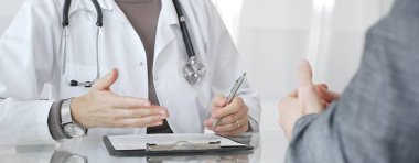 Doktor tedavi seçeneklerini ve tıbbi bilgileri modern hastane veya özel klinikteki hastalara danışarak açıklıyor. İlaç ve sağlık hizmetleri