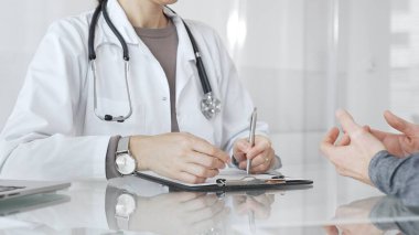 Doktor tedavi seçeneklerini ve tıbbi bilgileri modern hastane veya özel klinikteki hastalara danışarak açıklıyor. İlaç ve sağlık hizmetleri