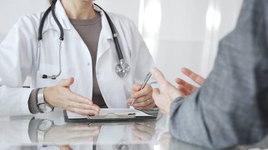 Doktor tedavi seçeneklerini ve tıbbi bilgileri modern hastane veya özel klinikteki hastalara danışarak açıklıyor. İlaç ve sağlık hizmetleri