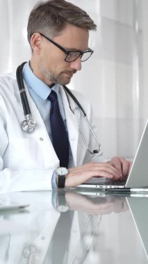 Beyaz önlük ve steteskop giyen doktor dizüstü bilgisayarda çalışıyor, teletıp danışmanlığı yapıyor ya da tıbbi rapor yazıyor. İlaç ve sağlık hizmetleri