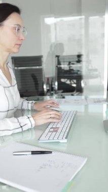 Ofisteki profesyonel kadın klavyede yazı yazıyor, piyasa grafiklerini ve mali verileri iş stratejisi için ekranda analiz ediyor. İş insanları kavramı