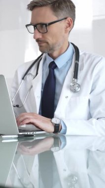 Beyaz önlük ve steteskop giyen doktor dizüstü bilgisayarda çalışıyor, teletıp danışmanlığı yapıyor ya da tıbbi rapor yazıyor. İlaç ve sağlık hizmetleri