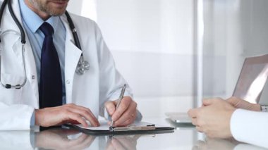 Doktor, açık modern bir klinikte hastaya danışmanlık yaparken panoya notlar yazıyor. Sağlık ve tıp konsepti. Tıp, sağlık ve bilim konsepti