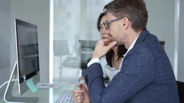 İş arkadaşları bilgisayar ekranında gösterilen finansal grafik ve grafikleri analiz ederek strateji ve piyasa performansını tartışıyor. İş insanları kavramı