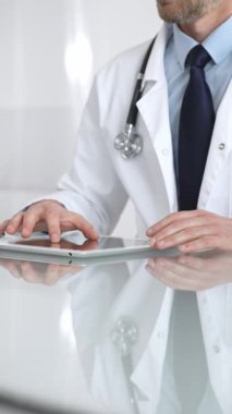 Doktor, teletıp, hasta verilerini ve sağlık teknolojisini temsil eden yansıtıcı bir masada dijital tablet tutuyor ve onunla etkileşime geçiyor. İlaç ve sağlık hizmetleri