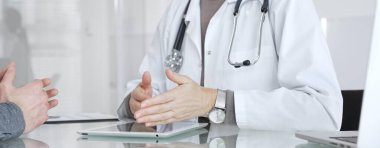 Doktor, klinik muayenesi, profesyonel bakım tartışması sırasında tıbbi verileri incelemek için tablet kullanan hastaya tedavi seçeneklerini açıklıyor. İlaç ve sağlık hizmetleri