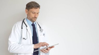 Steteskop ve beyaz önlük giyen kendine güvenen doktor kollarını kavuşturup düşünceli bir şekilde bakıyor. Tıbbi profesyonelliği ve uzmanlığı temsil ediyor. İlaç ve sağlık hizmetleri.