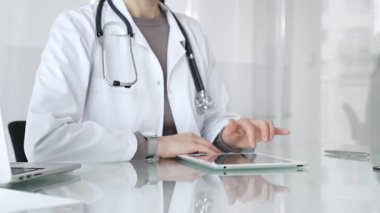 Doktor dijital tablete dokunuyor klinikteki tıbbi kayıtları inceliyor, sağlık uzmanı hastanedeki modern teknolojiyi kullanıyor. İlaç ve sağlık hizmetleri