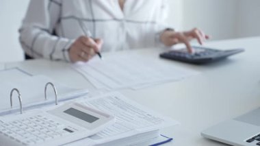 Muhasebecinin not aldığı, muhasebe, finans ve vergi hazırlıklarını vurguladığı mali dökümanlarla ilgili bir hesap makinesini kapatın. Ticarette denetim ve vergiler.