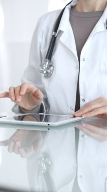 Steteskoplu beyaz önlüklü bir tıp uzmanı dijital sağlık hizmetleri, teletıp ve EMR veri incelemesi ve danışma için bir tablet kullanıyor. İlaç ve sağlık hizmetleri