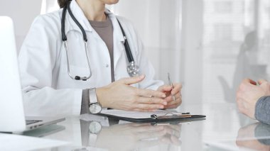 Doktor tedavi seçeneklerini ve tıbbi bilgileri modern hastane veya özel klinikteki hastalara danışarak açıklıyor. İlaç ve sağlık hizmetleri