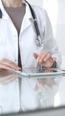 Steteskoplu beyaz önlüklü bir tıp uzmanı dijital sağlık hizmetleri, teletıp ve EMR veri incelemesi ve danışma için bir tablet kullanıyor. İlaç ve sağlık hizmetleri