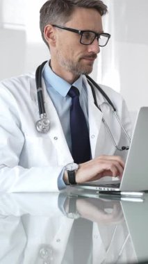 Beyaz önlük ve steteskop giyen doktor dizüstü bilgisayarda çalışıyor, teletıp danışmanlığı yapıyor ya da tıbbi rapor yazıyor. İlaç ve sağlık hizmetleri