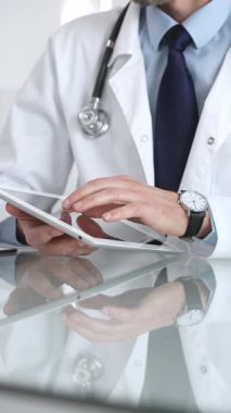 Doktor, teletıp, hasta verilerini ve sağlık teknolojisini temsil eden yansıtıcı bir masada dijital tablet tutuyor ve onunla etkileşime geçiyor. İlaç ve sağlık hizmetleri