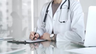 Panoya yazı yazan, steteskop takan, ilaç, sağlık, teşhis ve tedavi kavramlarını yansıtan beyaz önlüklü bir doktor. İlaç ve sağlık hizmetleri