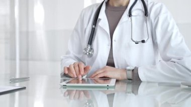 Doktor dijital tablete dokunuyor klinikteki tıbbi kayıtları inceliyor, sağlık uzmanı hastanedeki modern teknolojiyi kullanıyor. İlaç ve sağlık hizmetleri