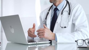 Beyaz önlüklü doktor internette el hareketleriyle tıbbi bilgileri açıklıyor, tele-sağlık iletişimi için dizüstü bilgisayar kullanıyor. Tıp, sağlık ve bilim konsepti
