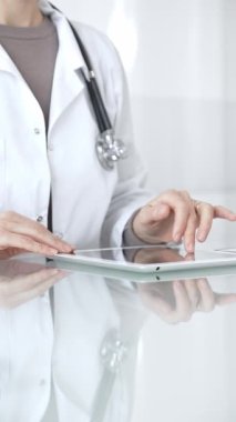 Steteskoplu beyaz önlüklü bir tıp uzmanı dijital sağlık hizmetleri, teletıp ve EMR veri incelemesi ve danışma için bir tablet kullanıyor. İlaç ve sağlık hizmetleri