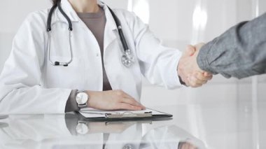 Doktor başarılı bir muayeneden sonra hastayı tokalaşarak selamlıyor. Güven, empati, tıbbi ortaklık ve anlaşma gösteriyor. İlaç ve sağlık hizmetleri