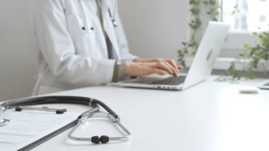 Tıbbi kayıtlar üzerinde steteskop var. Doktorun bilgisayarında yazdığı bilgisayarın karşısında duruyor. Bu da sağlık hizmeti ya da teletıp hizmetlerini gösteriyor. Tıp konsepti.