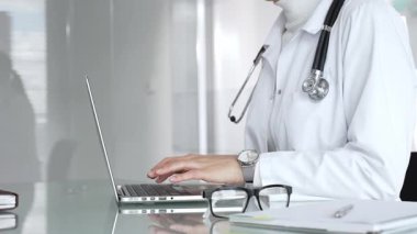Profesyonel kadın doktor online danışmanlık yapıyor ya da sağlık kliniğindeki bilgisayarla hasta kayıtlarını belgeliyor. Tıp, sağlık ve bilim konsepti