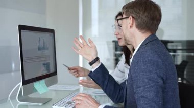 Bir projede işbirliği yapan iş ekibi, bilgisayar ekranında çizelge ve raporları analiz ederek stratejik planlama için veri kavrayışlarını tartışıyor. İş insanları kavramı