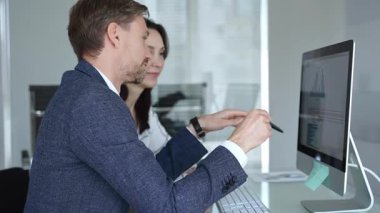 İş arkadaşları bilgisayar ekranında gösterilen finansal grafik ve grafikleri analiz ederek strateji ve piyasa performansını tartışıyor. İş insanları kavramı