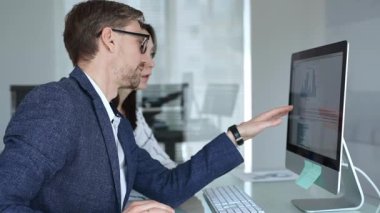 İş arkadaşları bilgisayar ekranında gösterilen finansal grafik ve grafikleri analiz ederek strateji ve piyasa performansını tartışıyor. İş insanları kavramı