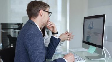 Bir projede işbirliği yapan iş ekibi, bilgisayar ekranında çizelge ve raporları analiz ederek stratejik planlama için veri kavrayışlarını tartışıyor. İş insanları kavramı