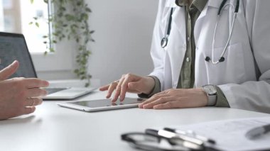 Dijital test sonuçlarını hastayla inceleyen kadın doktor, modern klinik ortamdaki tıbbi bulguları, sağlık teknolojisi etkileşimini tartışıyor. İlaç ve sağlık hizmetleri kavramı