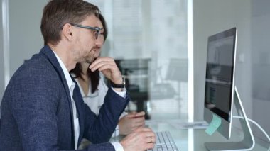 İş arkadaşları bilgisayar ekranında gösterilen finansal grafik ve grafikleri analiz ederek strateji ve piyasa performansını tartışıyor. İş insanları kavramı