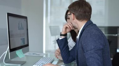 İş arkadaşları bilgisayar ekranında gösterilen finansal grafik ve grafikleri analiz ederek strateji ve piyasa performansını tartışıyor. İş insanları kavramı