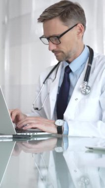 Beyaz önlük ve steteskop giyen doktor dizüstü bilgisayarda çalışıyor, teletıp danışmanlığı yapıyor ya da tıbbi rapor yazıyor. İlaç ve sağlık hizmetleri