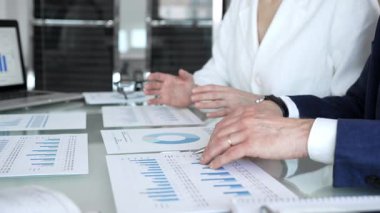 İş dünyasından profesyoneller, büyüme ve performans odaklı bir toplantıda dizüstü bilgisayar grafiklerine ve belgelere işaret ederek mali verileri analiz ediyor ve planlama stratejisini inceliyor.