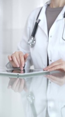 Steteskoplu beyaz önlüklü bir tıp uzmanı dijital sağlık hizmetleri, teletıp ve EMR veri incelemesi ve danışma için bir tablet kullanıyor. İlaç ve sağlık hizmetleri