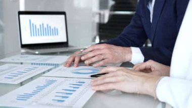 Şirket toplantısında mali raporları ve grafikleri analiz eden iş adamları, strateji üzerinde işbirliği yapan, veri analizlerini inceleyen ve ofiste bir dizüstü bilgisayarla çalışan iş adamları.