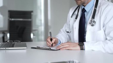 Tıp bürosunda dijital tabletle çalışan, sağlık hizmetleri danışmanlığı sağlayan, tanı ve hasta verileri için teknolojiyi kullanan bir doktor. Tıp, sağlık ve bilim konsepti