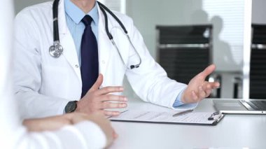 Beyaz önlüklü ve steteskop hastası olan bir doktor profesyonel ofis ortamında sağlık bilgileri ve tedavi seçeneklerini açıklıyor. Tıp, sağlık ve bilim konsepti