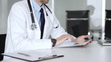 Beyaz önlüklü doktor ve steteskop modern dijital tablet üzerinde yazarak hastalara sağlık hizmeti ve sanal destek sağlıyor. Tıp, sağlık ve bilim konsepti