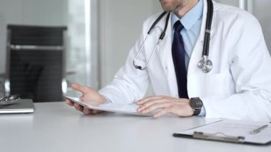 Beyaz önlüklü doktor ve steteskop modern dijital tablet üzerinde yazarak hastalara sağlık hizmeti ve sanal destek sağlıyor. Tıp, sağlık ve bilim konsepti