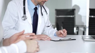 Beyaz önlüklü ve steteskop hastası olan bir doktor profesyonel ofis ortamında sağlık bilgileri ve tedavi seçeneklerini açıklıyor. Tıp, sağlık ve bilim konsepti