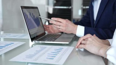 Şirket toplantısında mali raporları ve grafikleri analiz eden iş adamları, strateji üzerinde işbirliği yapan, veri analizlerini inceleyen ve ofiste bir dizüstü bilgisayarla çalışan iş adamları.