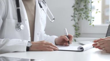 Doktor, parlak ve modern bir klinikteki muayene sırasında hasta sağlığıyla ilgili endişeleri dinliyor ve reçete yazıyor. İlaç ve sağlık hizmetleri kavramı.