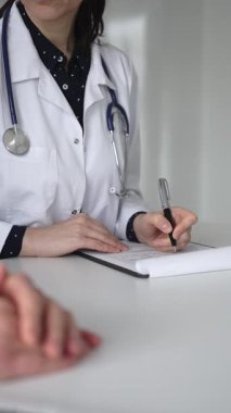 Beyaz önlüklü doktor, bir hastayla tıbbi istişare sırasında panoya notlar yazarak sağlık ve tedaviyi tartışıyor. Tıp, sağlık ve bilim konsepti