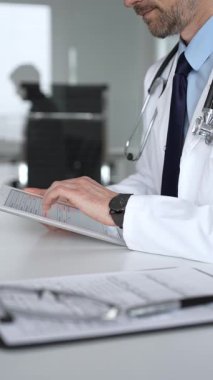 Doktorun hastaya danışması, bir klinik masasında tablet kullanması modern tıp ve dijital sağlık hizmetleri teşhisini sembolize ediyor. Tıp, sağlık ve bilim konsepti